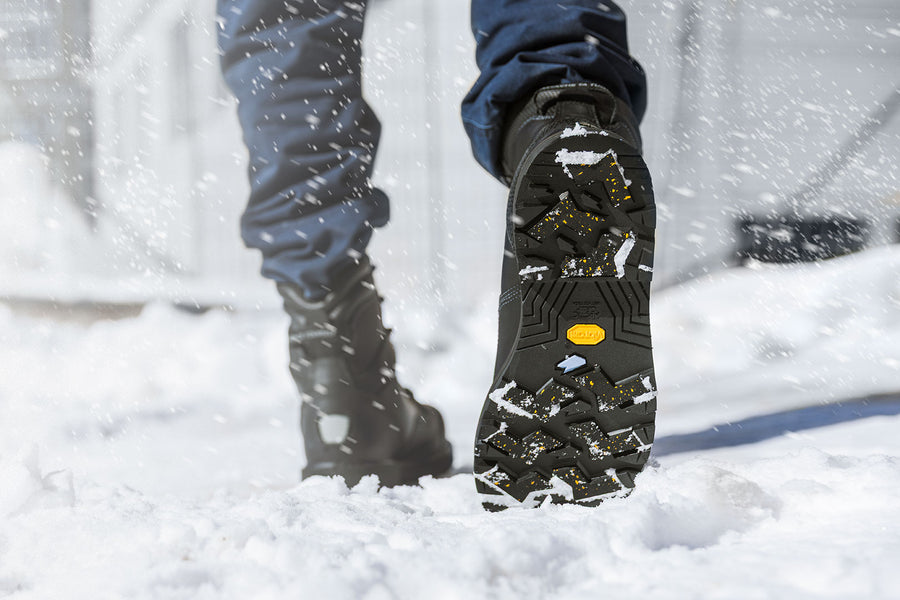 Person wearing black Agility Arctic Grip work boots with Vibram outsoles for wet and dry ice.